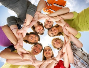 Large group of smiling friends staying together and looking at camera isolated on blue background
