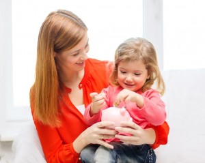 family, children, money, investmen and happy people concept - happy mother and daughter with small pink piggy bank